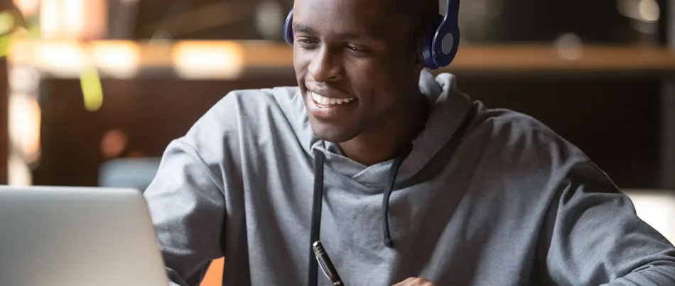 A man using his computer and headphones